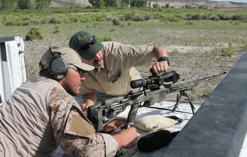 Two guys at the range adjusting their rifle scope